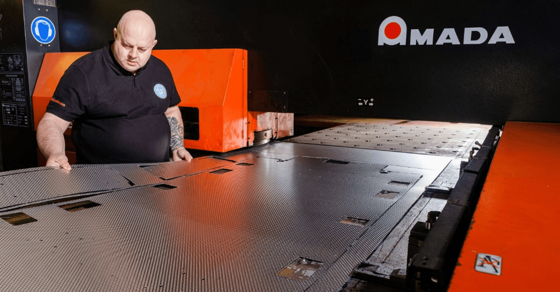 A staff member making a guitar flight case from a sheet of aluminium
